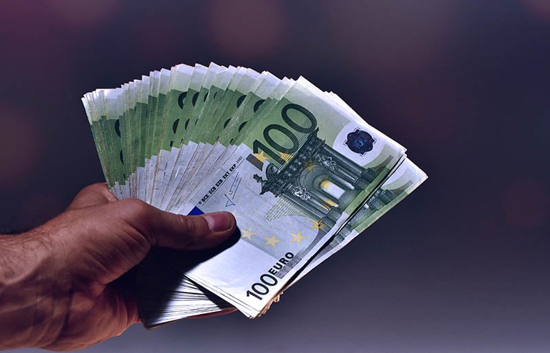une main montrant de nombreux billets de 100 euros